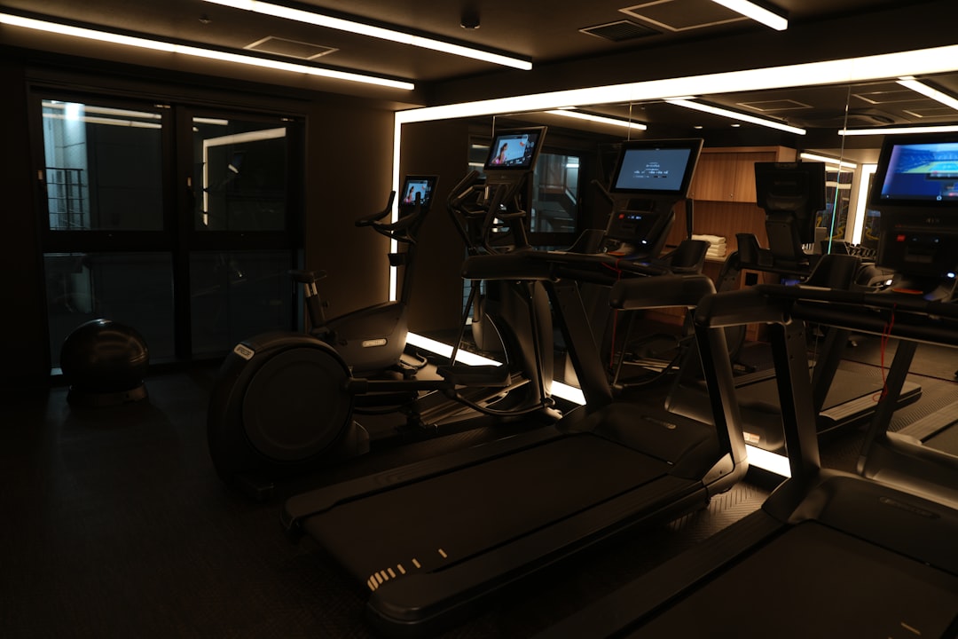 A dimly lit gym with treadmills and monitors