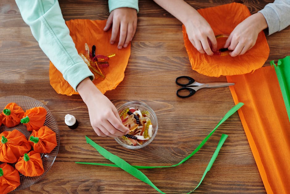 Two children preparing treats with candies and wrapping them creatively for Halloween festivities.