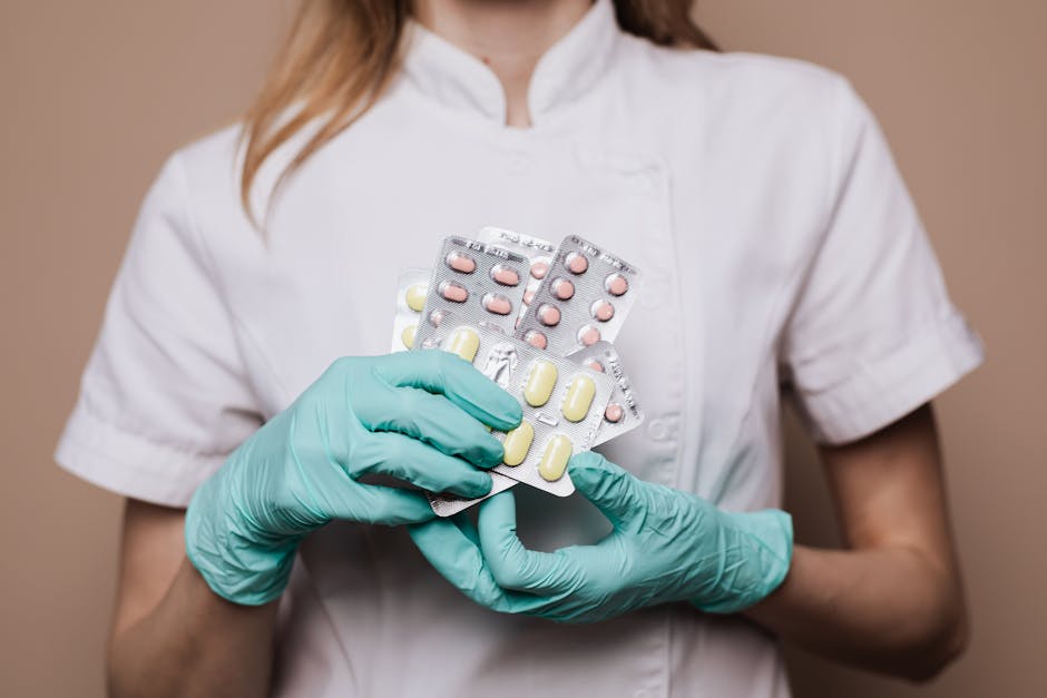 Close-up of a healthcare professional wearing gloves and holding blister packs of medication.