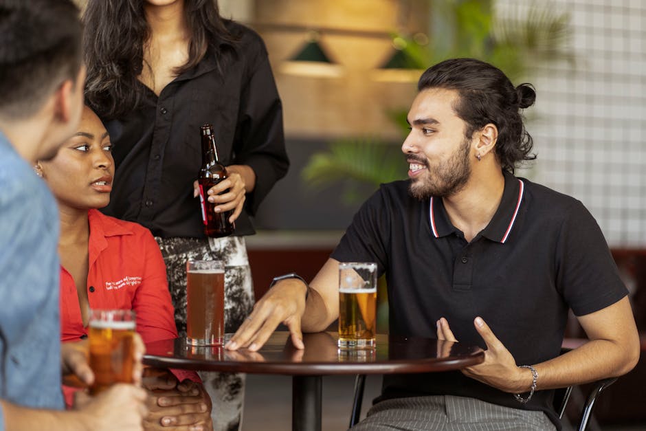 Group of friends enjoying drinks and conversation indoors at a table.