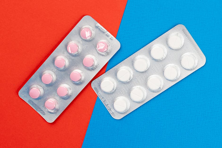 Flat lay of pink and white tablets in blister packs on a vibrant contrasting background.