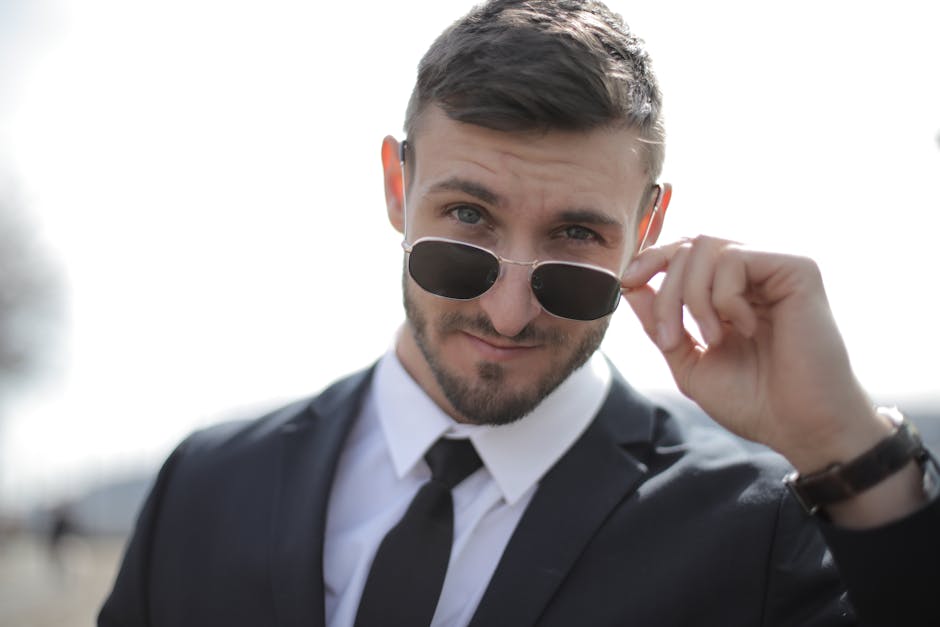 Portrait of a confident businessman in a black suit and sunglasses outdoors.