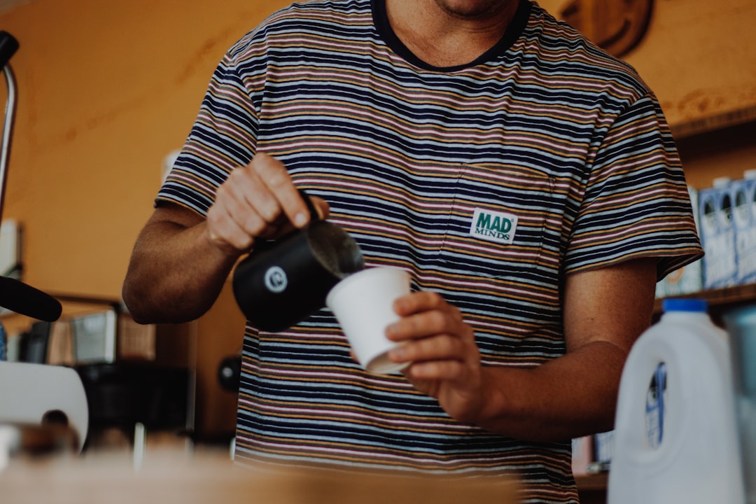 Barista pouring milk into a cup for coffee.