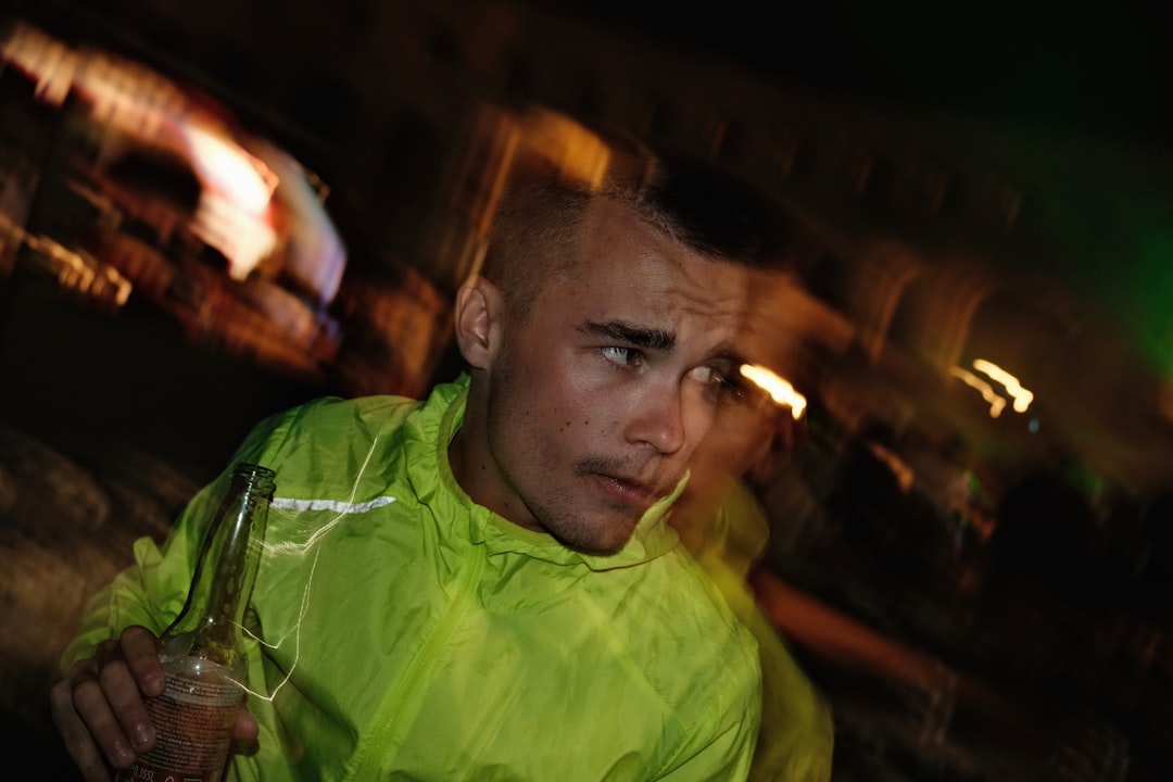 Man in neon jacket holding bottle at night