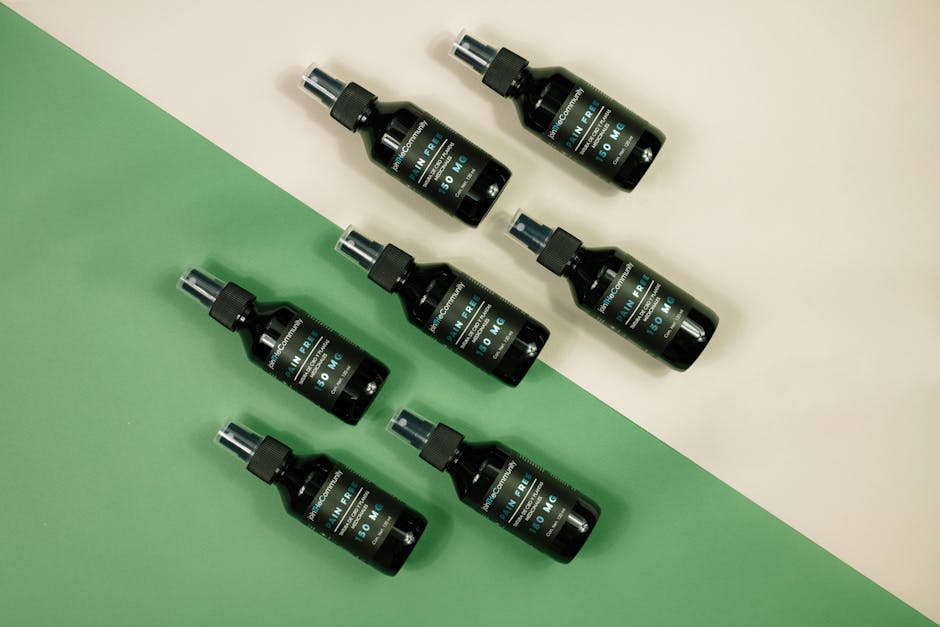 Stylish arrangement of cosmetic spray bottles on green and beige backdrop, perfect for product promotions.