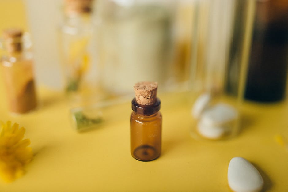 A small glass bottle with a cork on a vibrant yellow background, surrounded by soft elements.