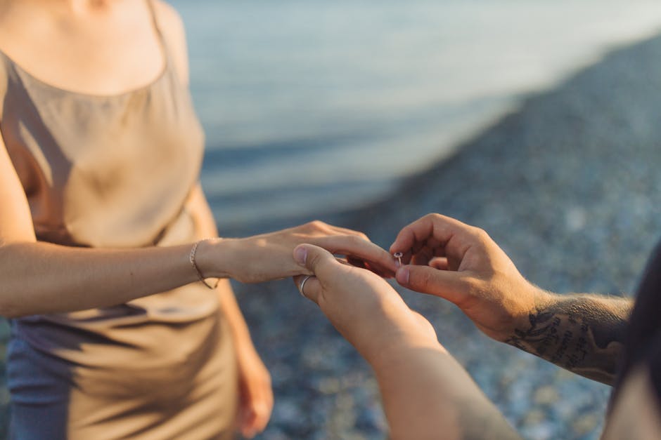 A couple getting engaged by the sea, capturing a romantic moment at sunset.