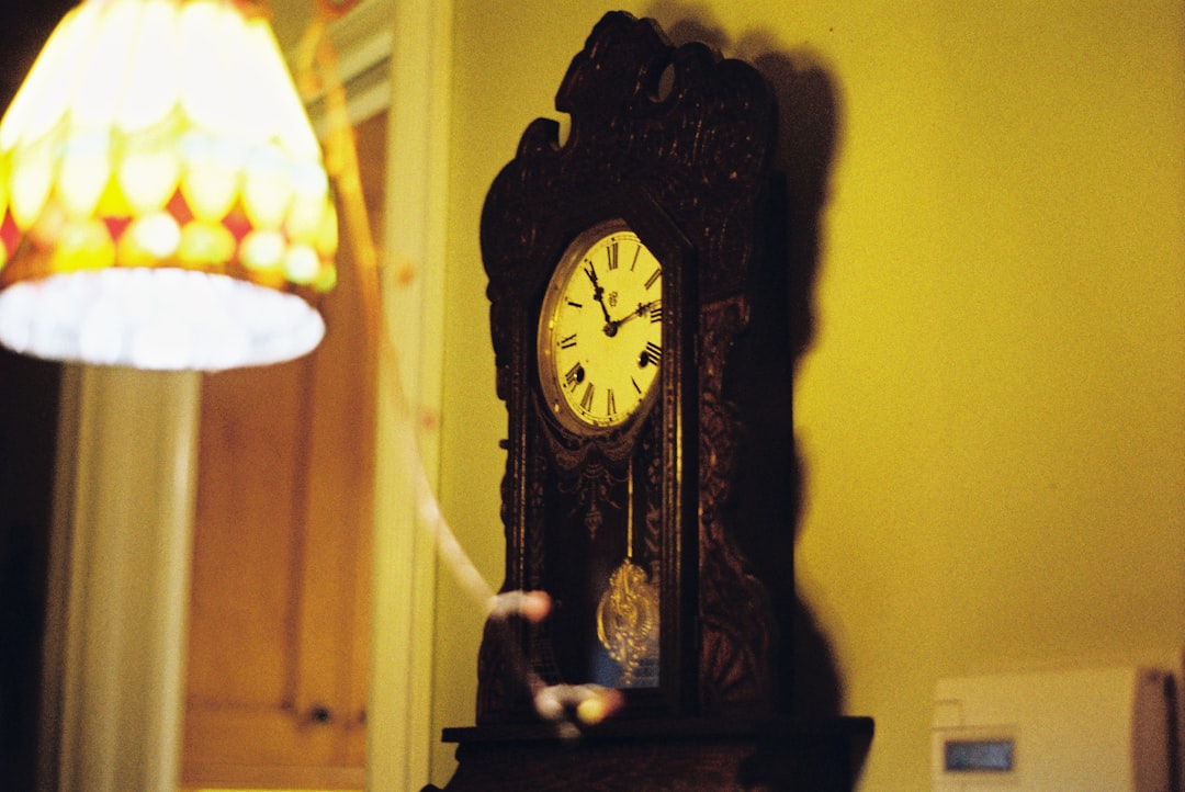 a grandfather clock sitting on top of a table next to a lamp