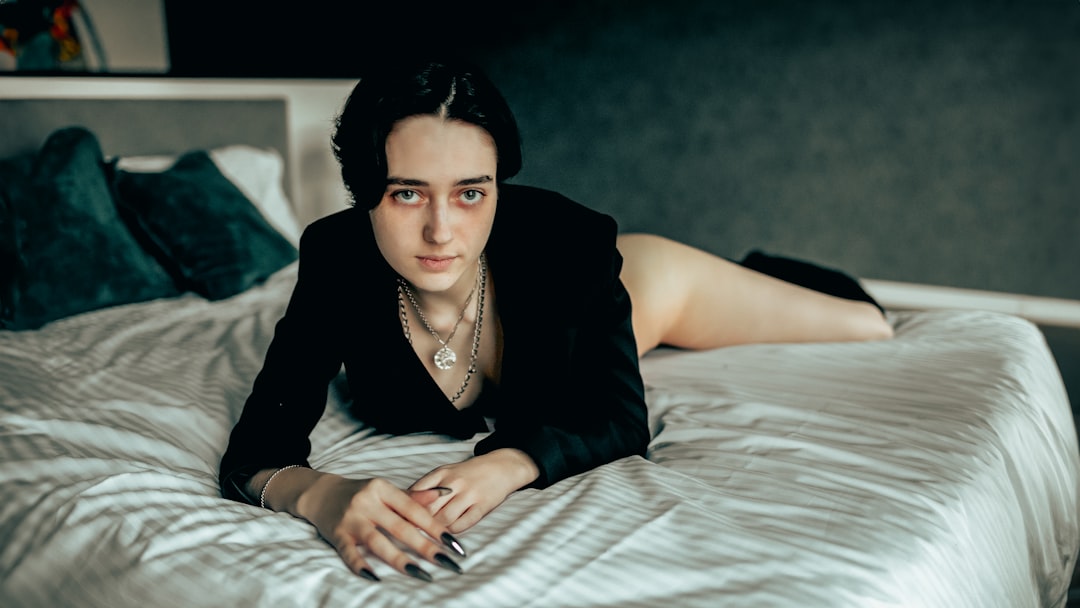 Woman in black blazer lying on a bed.