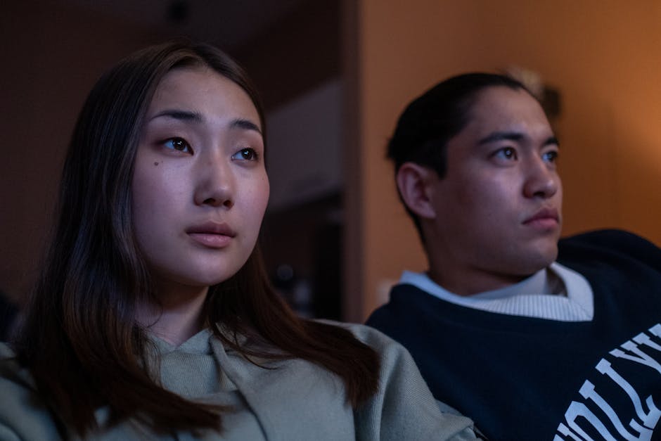Close-up of a young couple watching a movie together in their cozy living room.